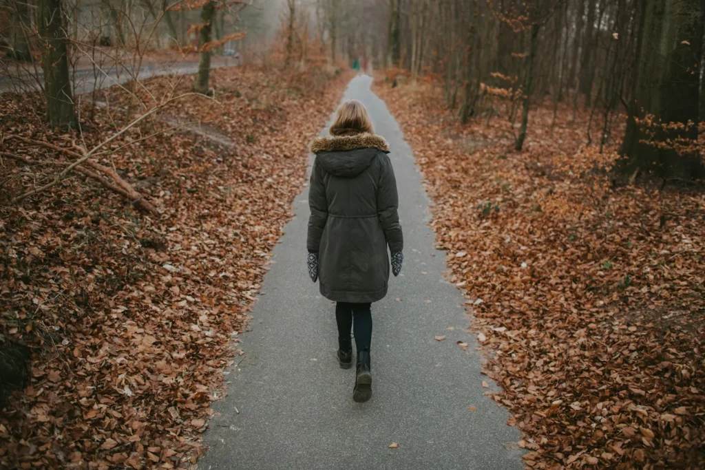 Personne marchant sur un chemin couvert de feuilles mortes